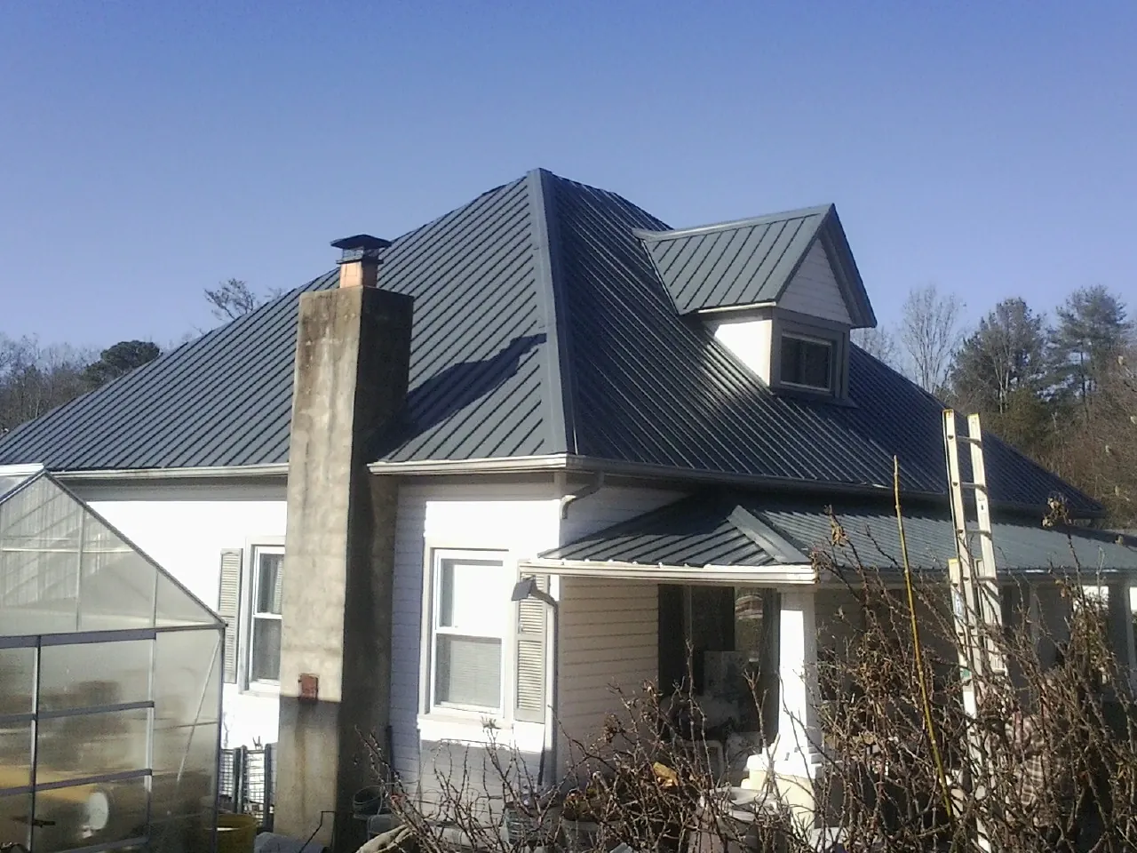 Dark blue standing seam metal roof on a white farmhouse with dormer — Slate & Tile Roof Repair by Roofing Brothers in Veedersburg