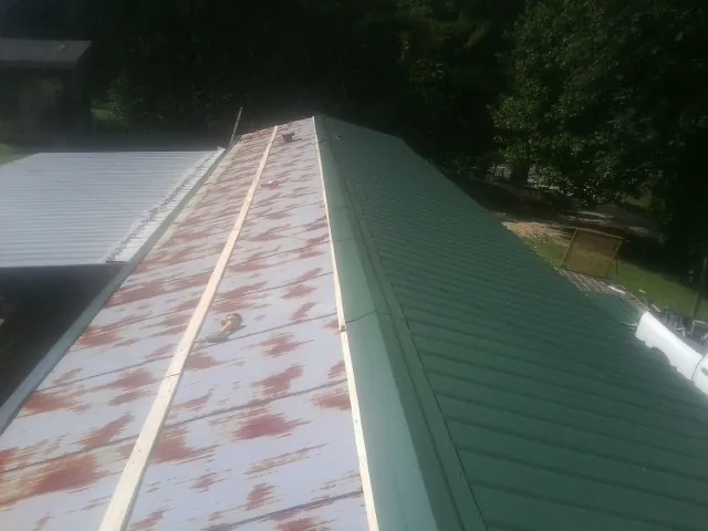 Old rusted panels beside newly installed green metal roofing — Wind Damage Roof Repair by Roofing Brothers in Veedersburg