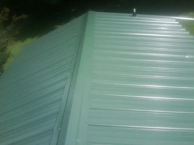 New green metal panels meeting at the ridge of a roof — Flat Roof Repair work by our crew in Veedersburg