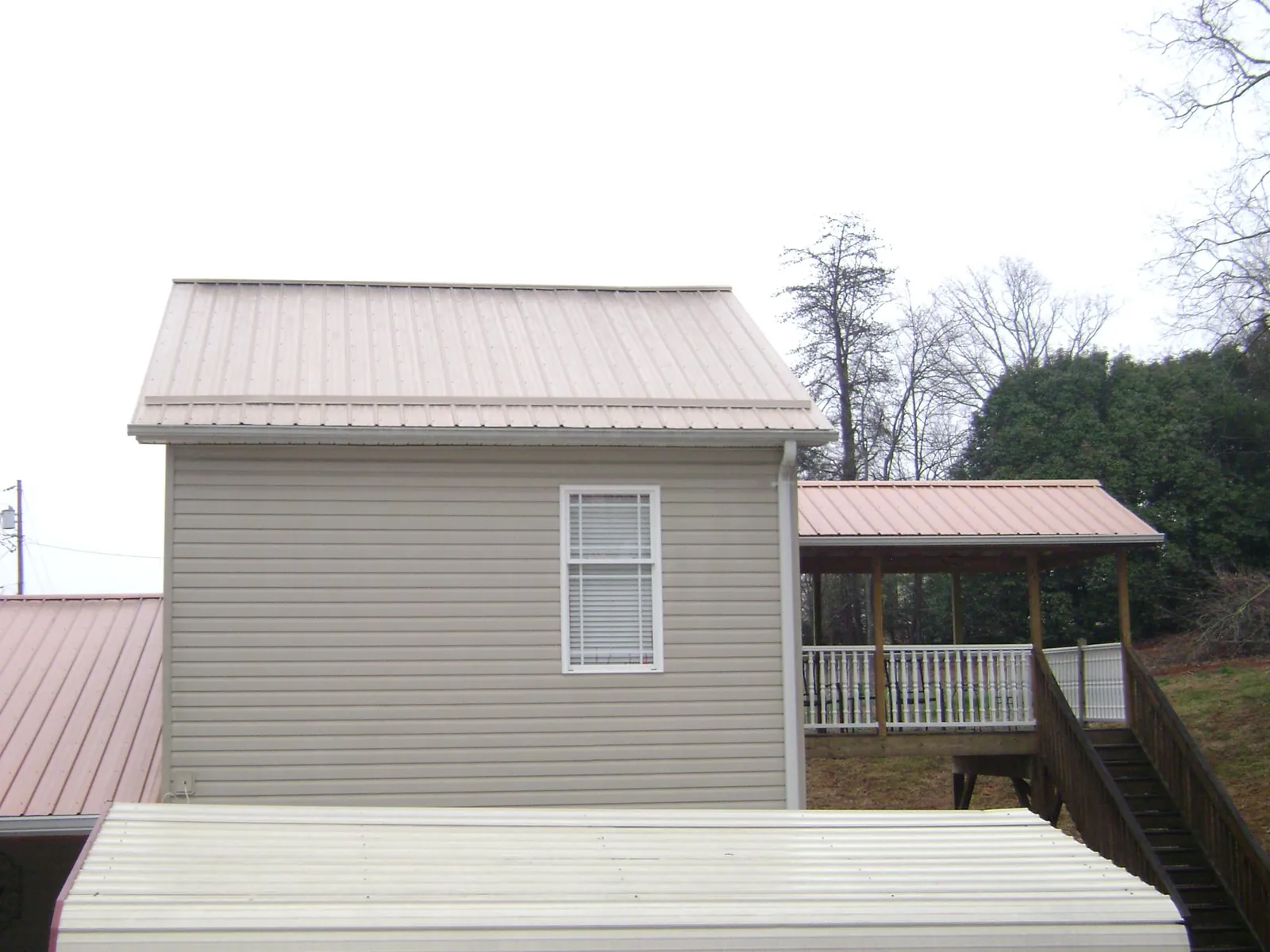 Tan metal roofs on a two story addition and attached porch, from a Roof Replacement job in Veedersburg