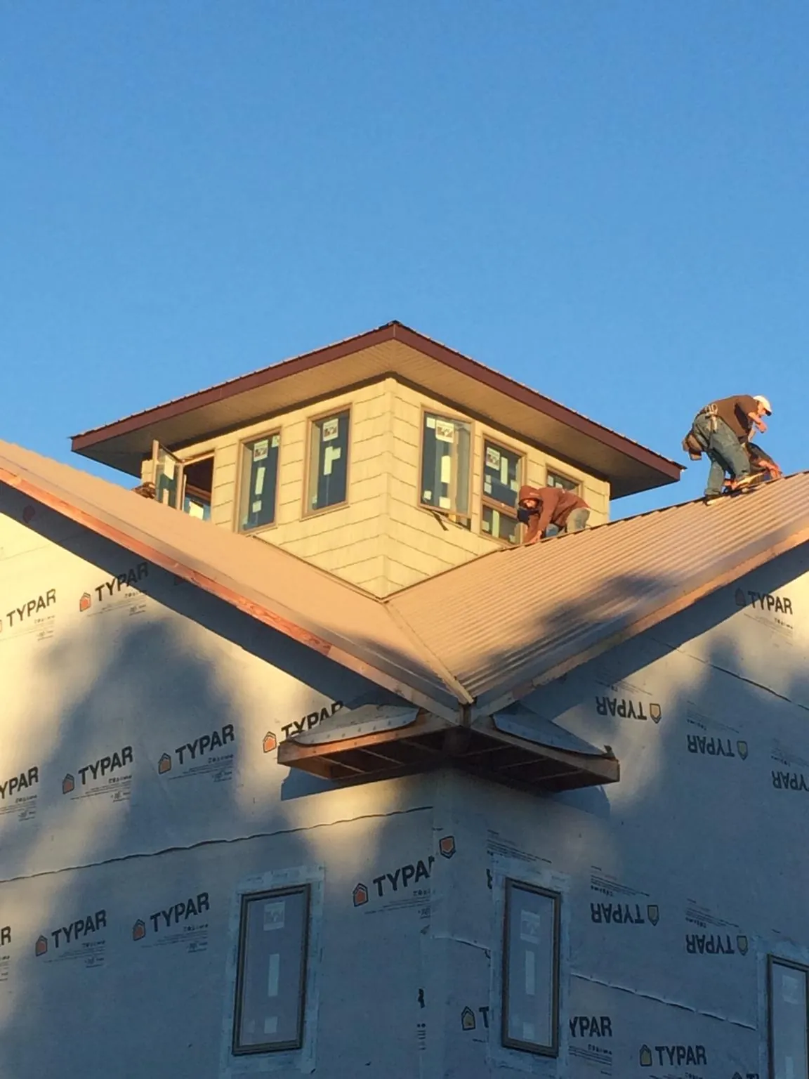 Roofers working around a rooftop cupola on a new metal roof at sunset — Roof Waterproofing in Veedersburg by Roofing Brothers